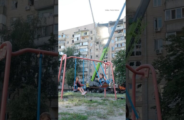 Children swing on a playground beside a building struck by a Russian attack in Kyiv on July 6